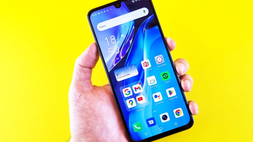 A hand holding an Android smartphone against a yellow background.