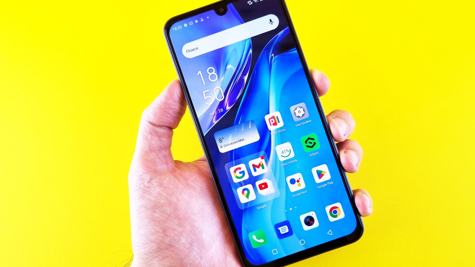 A hand holding an Android smartphone against a yellow background.