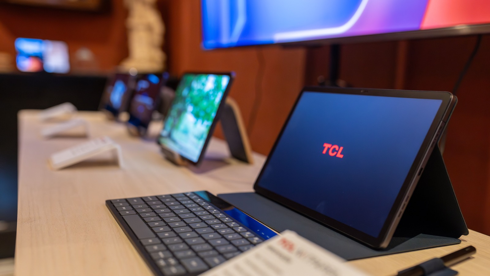 TCL tablet with an attached keyboard on a display table, with other tablets behind it.